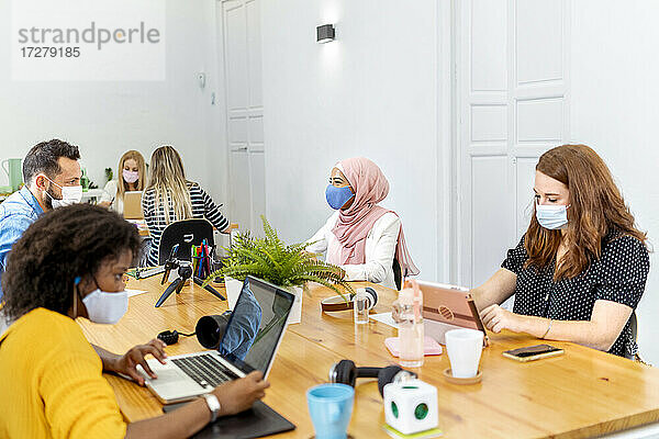Geschäftsleute mit Gesichtsmaske bei der Arbeit im Büro