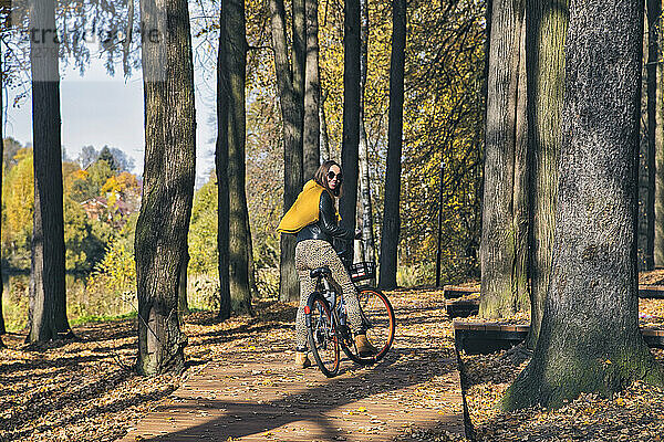 Frau schaut beim Fahrradfahren in einem öffentlichen Park über die Schulter