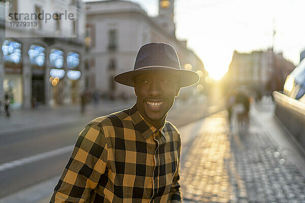 Lächelnder afrikanischer Mann bei Sonnenuntergang auf dem Gehweg stehend