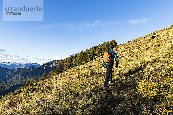 Männlicher Wanderer beim Aufstieg auf einen Berg an einem sonnigen Tag