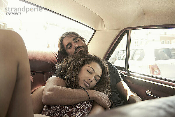 Junges Paar schläft im Auto an einem sonnigen Tag