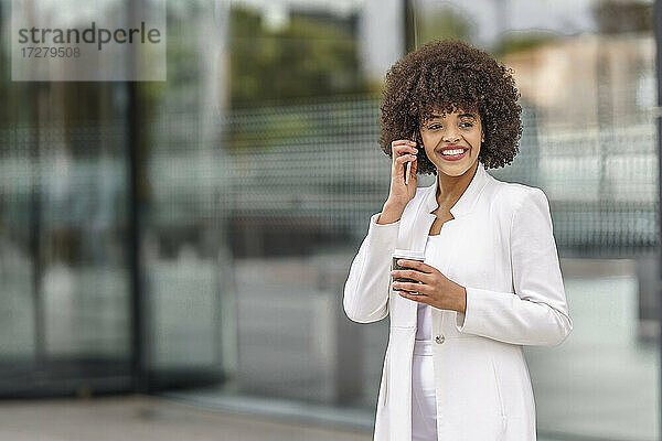 Lächelnde Geschäftsfrau  die im Freien stehend mit ihrem Handy telefoniert