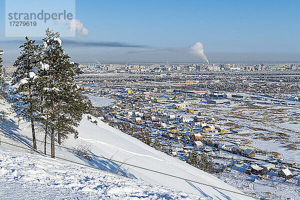 Russland  Republik Sacha  Jakutsk  Schneebedeckter Hügel mit Stadthäusern im Hintergrund