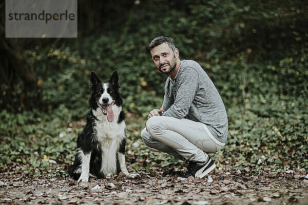 Mann kauert bei Hund in öffentlichem Park