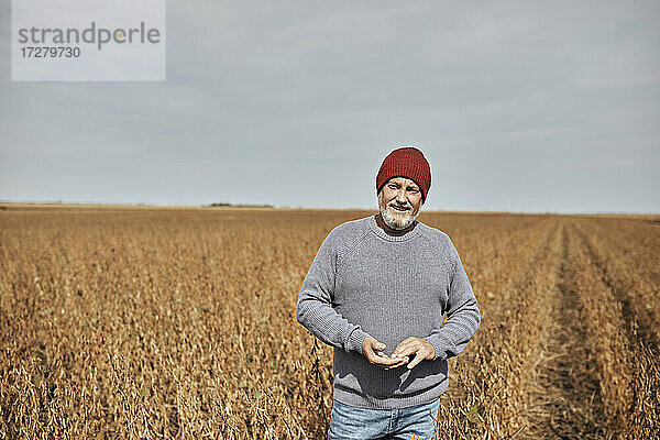 Landwirt mit Strickmütze auf einem Sojabohnenfeld bei klarem Himmel