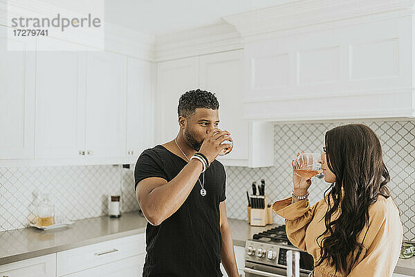 Paar trinkt Wein  während es in der Küche zu Hause steht