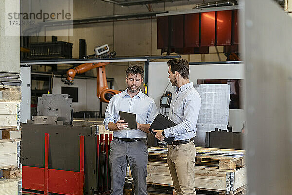 Geschäftsleute im Gespräch mit einem digitalen Tablet in einer Fabrik