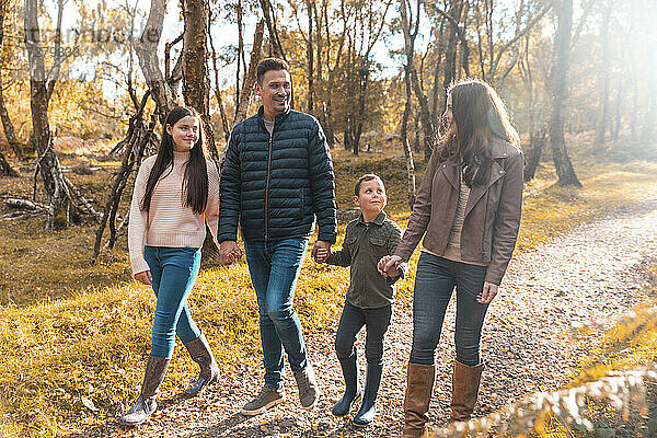 Familie  die sich gegenseitig anschaut  während sie im Herbst im Park spazieren geht