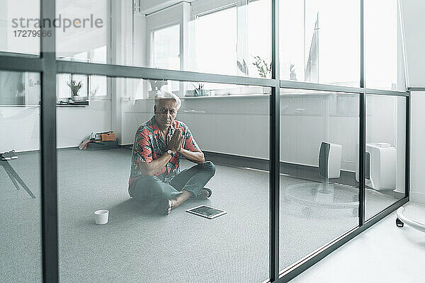 Geschäftsmann sitzt im Gebet Position auf dem Boden im Büro