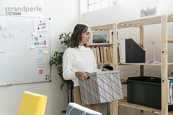 Geschäftsfrau trägt Kiste beim Einrichten eines neuen Büros
