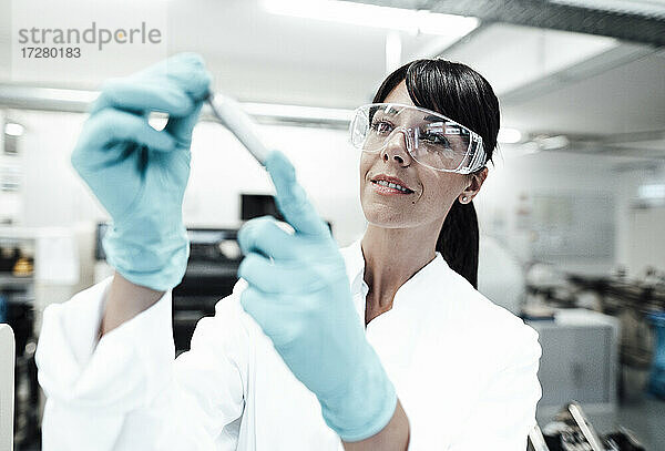 Lächelnde reife Wissenschaftlerin betrachtet eine Probe im Labor