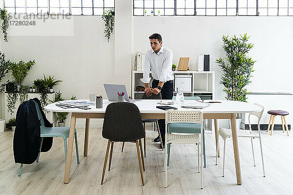 Geschäftsmann schaut auf den Laptop auf dem Schreibtisch  während er im Kreativbüro eine Strategie plant
