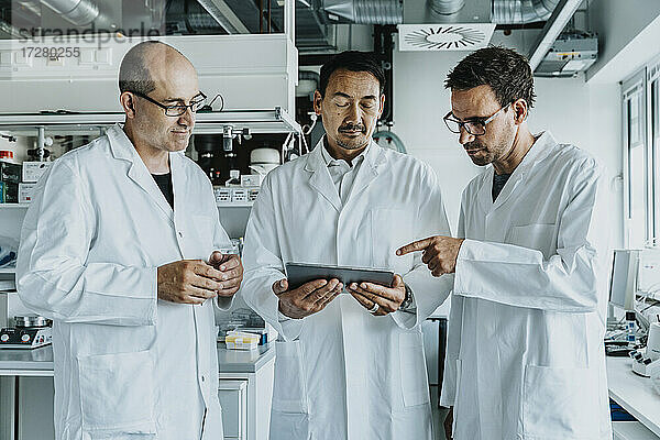 Ein Team von Wissenschaftlern benutzt ein digitales Tablet  während sie im Labor stehen