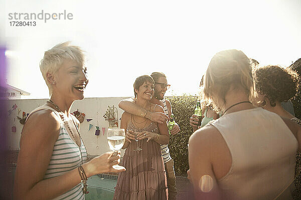 Weibliche und männliche Freunde genießen den Sommer beim Trinken von Alkohol gegen den Himmel