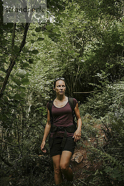 Frau beim Wandern inmitten von Grünpflanzen im Wald