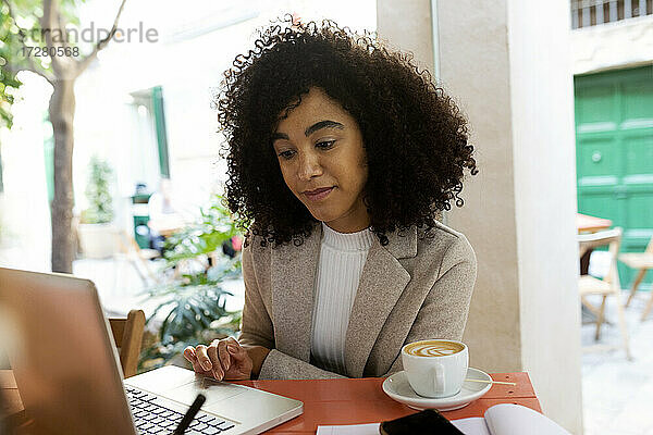 Unternehmerin  die im Café sitzend am Laptop arbeitet