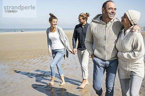 Junges und reifes Paar gehen zusammen am Strand spazieren
