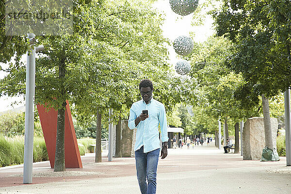 Älterer Mann Textnachrichten auf Smartphone beim Spaziergang im Park