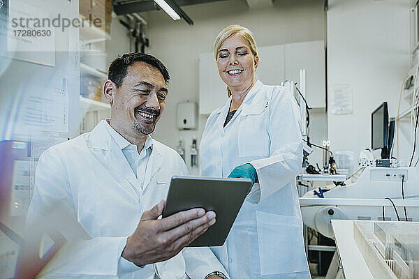 Wissenschaftlerin lächelt bei der Verwendung eines digitalen Tablets im Labor