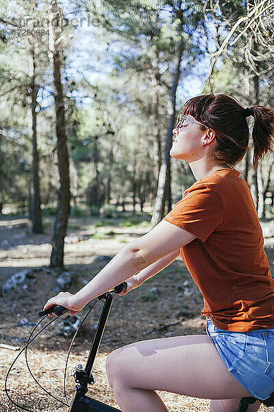 Junge Frau in Freizeitkleidung fährt am Wochenende Fahrrad auf dem Lande