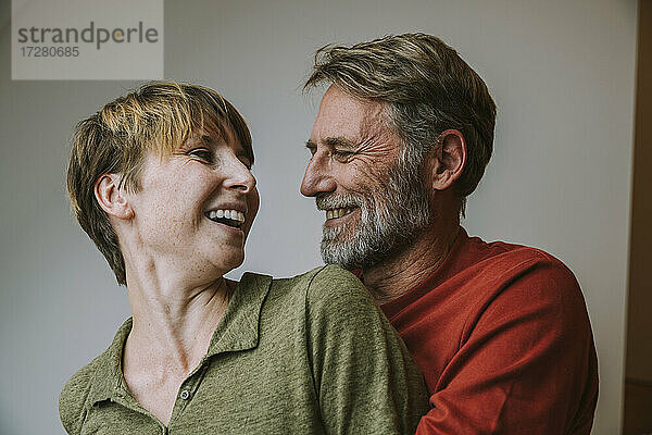 Lächelndes Paar  das sich umarmt  während es zu Hause steht