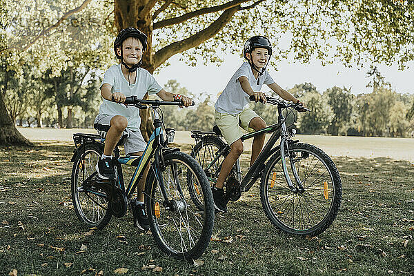 Brüder beim Radfahren im öffentlichen Park an einem sonnigen Tag