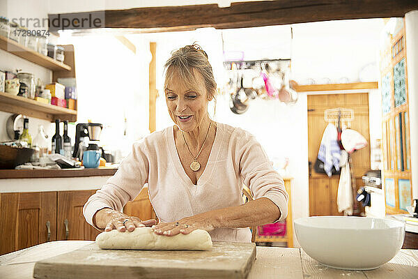Ältere Frau bereitet Teig vor  während sie in der Küche sitzt
