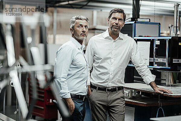 Männliche Ingenieure in Arbeitskleidung stehen an einer Werkbank in einer Fabrik