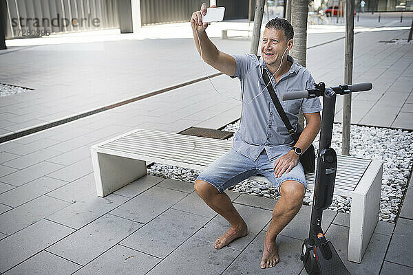 Reifer Mann  der ein Selfie macht  während er auf einer Bank sitzt