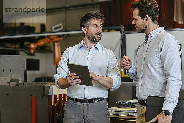 Geschäftsleute im Gespräch mit einem digitalen Tablet in einer Fabrik
