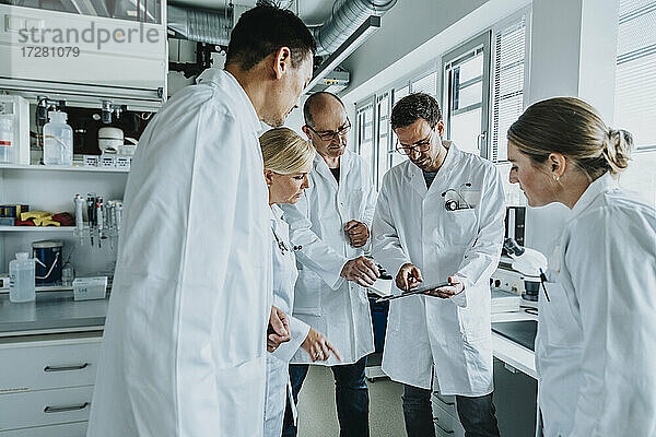 Wissenschaftler bei der Arbeit mit einem digitalen Tablet  während er im Labor steht