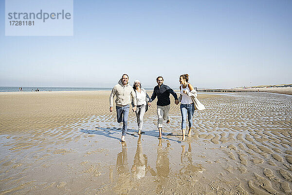Glückliche Familie  die sich beim Laufen am Strand an den Händen hält