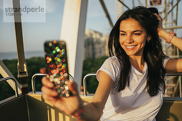 Glückliche schöne Frau nimmt Selfie auf Riesenrad im Vergnügungspark