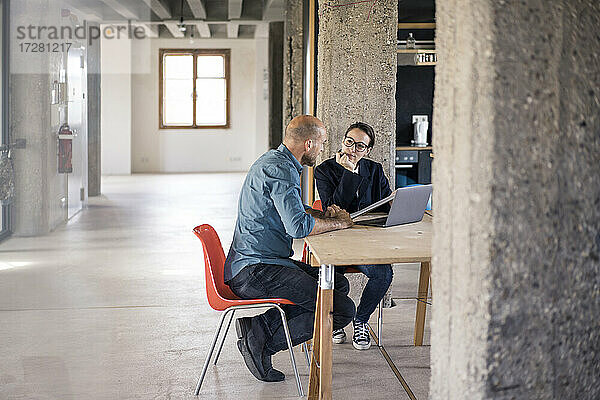 Geschäftsmann und Frau diskutieren bei der Benutzung eines Laptops im Büro