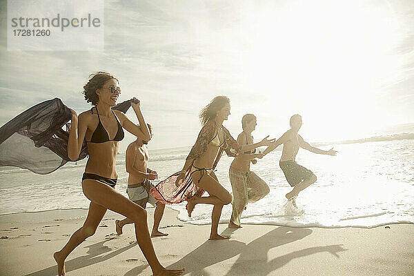 Gruppe von Freunden läuft am Strand an einem sonnigen Tag