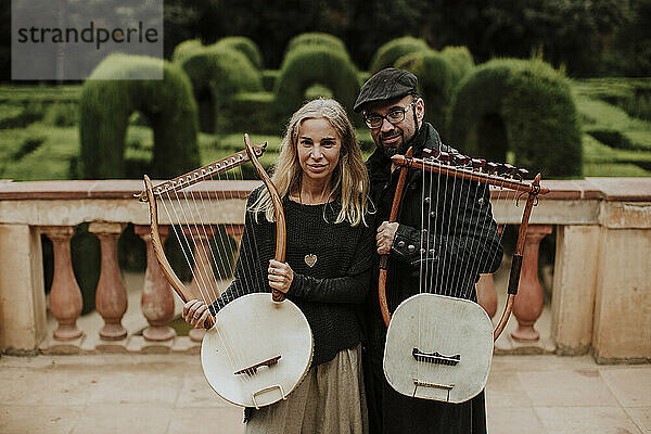 Männlicher und weiblicher Partner halten ein Lyra-Instrument in einem öffentlichen Park