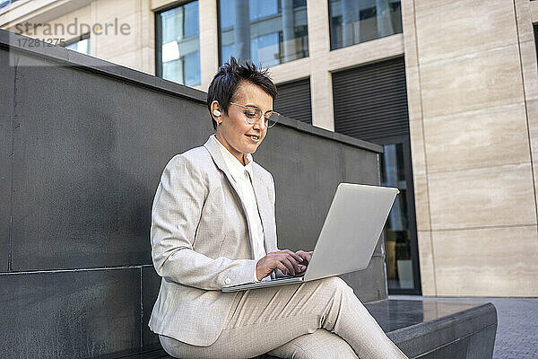 Geschäftsfrau  die einen Laptop benutzt  während sie auf einer Bank in der Stadt sitzt