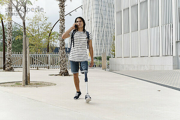 Mann mit Beinprothese telefoniert beim Stadtbummel mit Handy