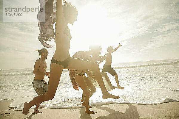 Fröhliche Freunde springen am Strand an einem sonnigen Tag