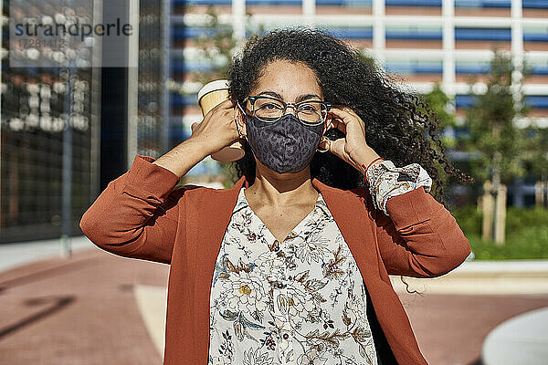 Junge Frau mit Gesichtsschutzmaske in der Stadt an einem sonnigen Tag