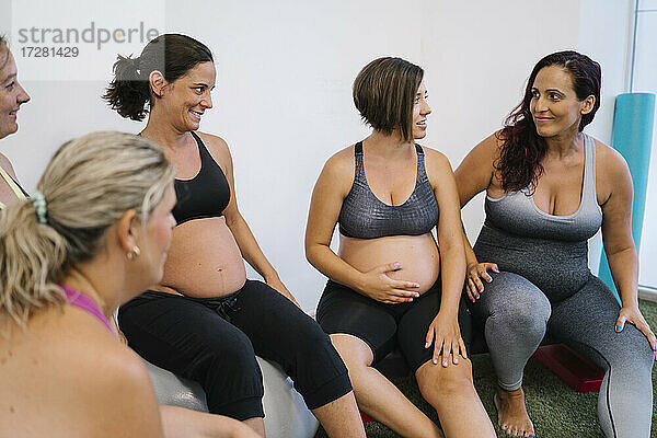 Gruppe schwangerer Frauen  die sich im Yogastudio miteinander unterhalten