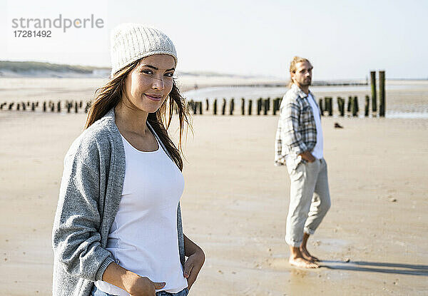 Lächelnde junge Frau mit Mann am Strand an einem sonnigen Tag