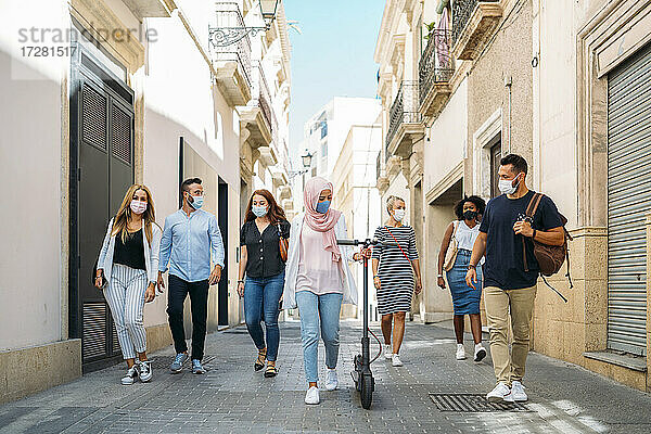Freunde mit Gesichtsmasken gehen auf der Straße in der Stadt