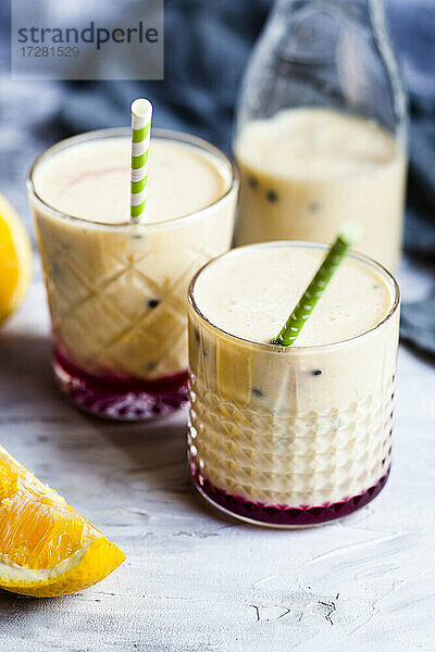 Gläser mit frischem Fruchtsmoothie mit Orangen  Bananen  Joghurt und Grenadine
