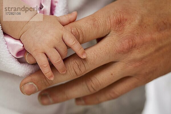 Baby Mädchen winzige Hand hält rauen Finger von Papa