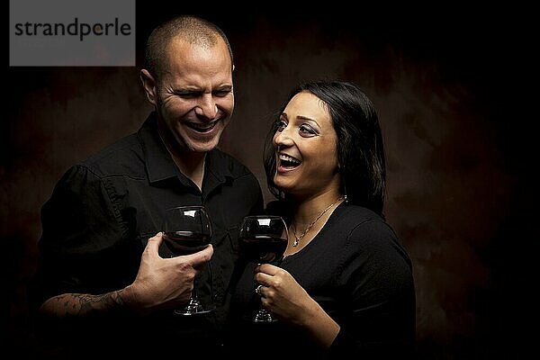 Glückliche junge gemischtrassige Paar hält Weingläser gegen einen schwarzen Hintergrund