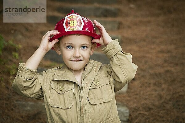 Glücklich adorable Kind Junge mit Feuerwehrmann Hut draußen spielen