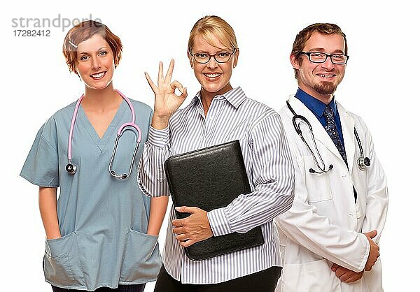Geschäftsfrau macht okay Handzeichen mit zwei Ärzten oder Krankenschwestern vor einem weißen Hintergrund