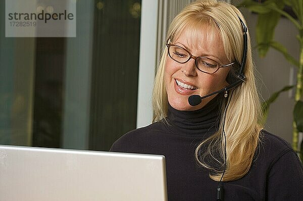 Attraktive Geschäftsfrau lächelt  während sie über ihr Telefon-Headset spricht