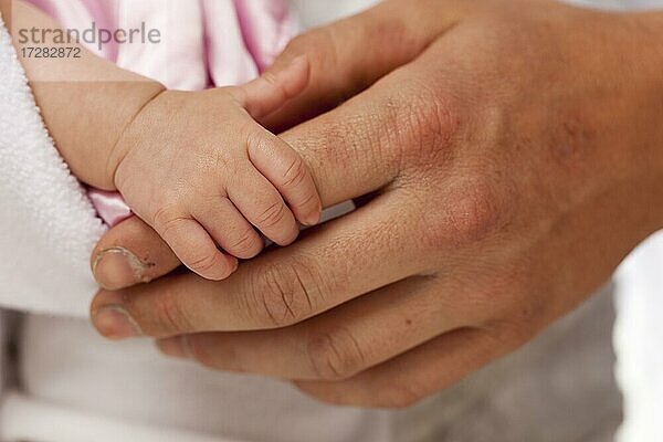 Baby Mädchen winzige Hand hält rauen Finger von Papa